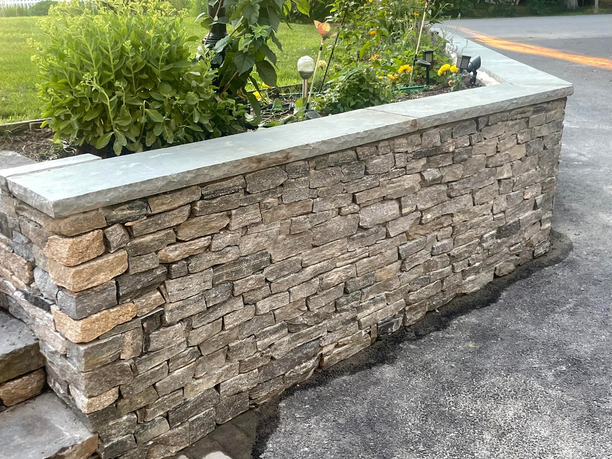Stone veneer wall with bluestone cap along a driveway