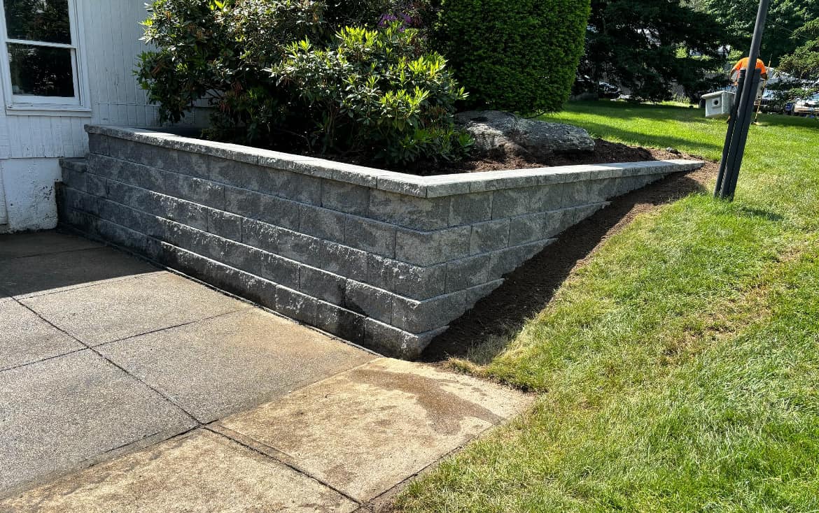 Block retaining wall holding back a planted slope